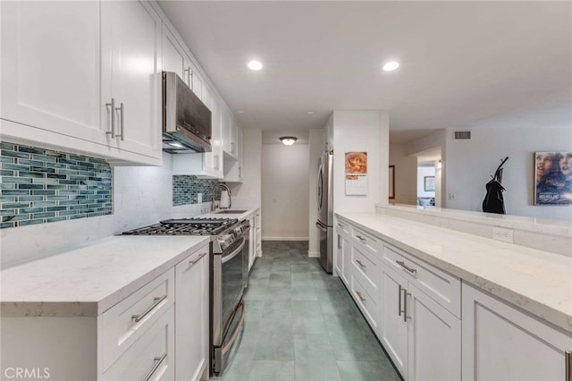 1940 N Highland Ave Unit 69, Los Angeles, CA 90068 - kitchen featuring stainless steel appliances, white cabinetry, tasteful backsplash, light stone counters, and recessed lighting