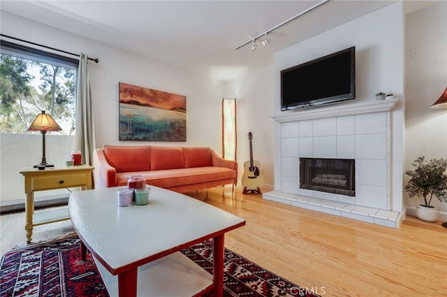 living room with track lighting, wood finished floors, and a tiled fireplace
