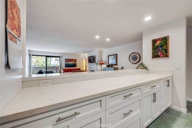 kitchen featuring light stone countertops, white cabinetry, open floor plan, recessed lighting, and baseboards