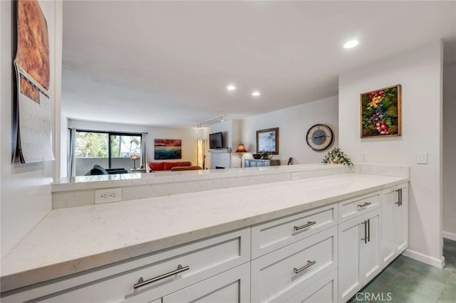 1940 N Highland Ave Unit 69, Los Angeles, CA 90068 - kitchen featuring light stone counters, white cabinets, recessed lighting, open floor plan, and a peninsula