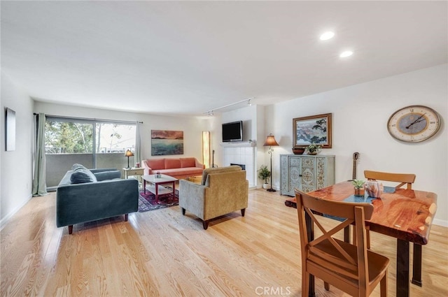 living room featuring baseboards, recessed lighting, light wood finished floors, and a tiled fireplace