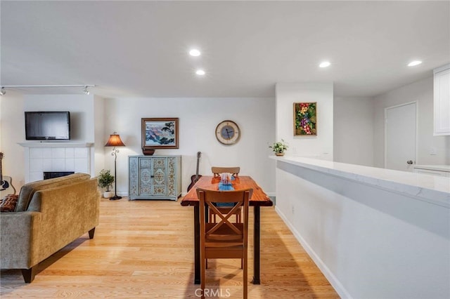 dining space featuring a fireplace, recessed lighting, baseboards, and light wood-style floors