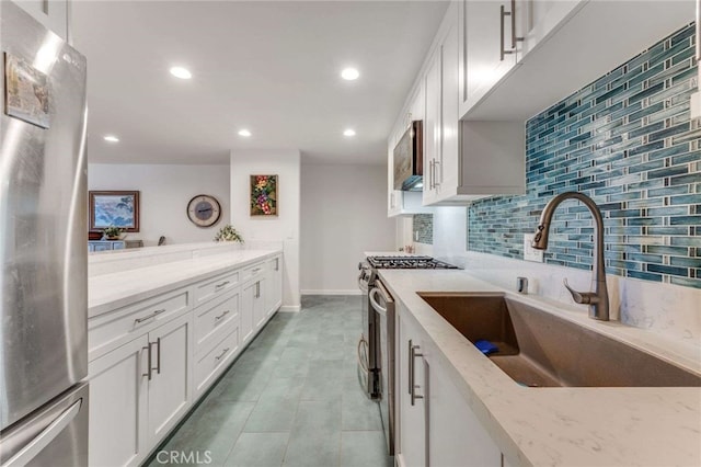 kitchen with decorative backsplash, white cabinetry, light stone counters, a sink, and stainless steel appliances