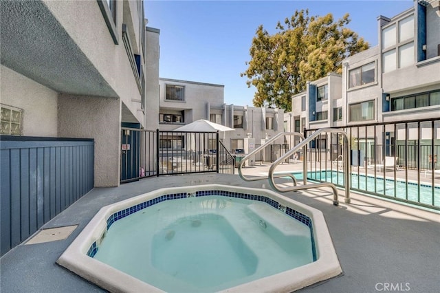 pool with fence, a community hot tub, and a residential view