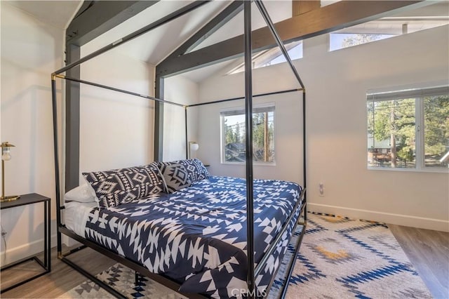 bedroom with high vaulted ceiling, baseboards, wood finished floors, and beam ceiling