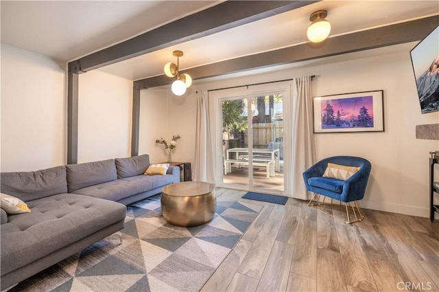 living room featuring baseboards, wood finished floors, and beam ceiling