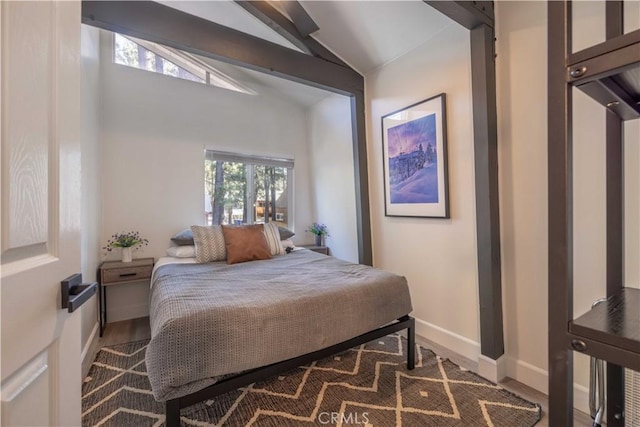 bedroom featuring baseboards and vaulted ceiling with beams