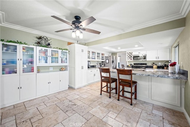 28863 Capano Bay Ct, Menifee, CA 92584 - kitchen with stainless steel appliances, a peninsula, glass insert cabinets, ornamental molding, and white cabinets