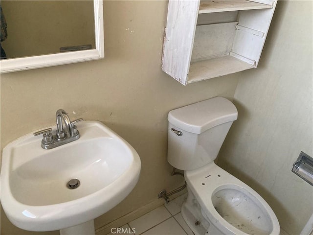 half bathroom with tile patterned flooring, toilet, and a sink