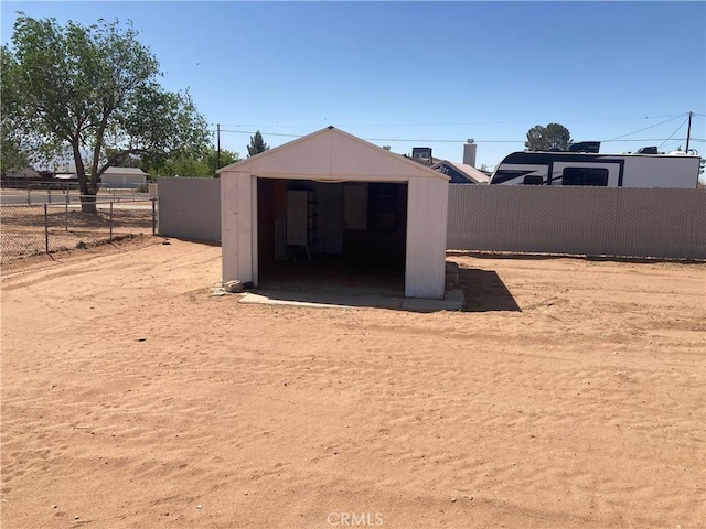 rear view of property with fence, a storage unit, and an outbuilding