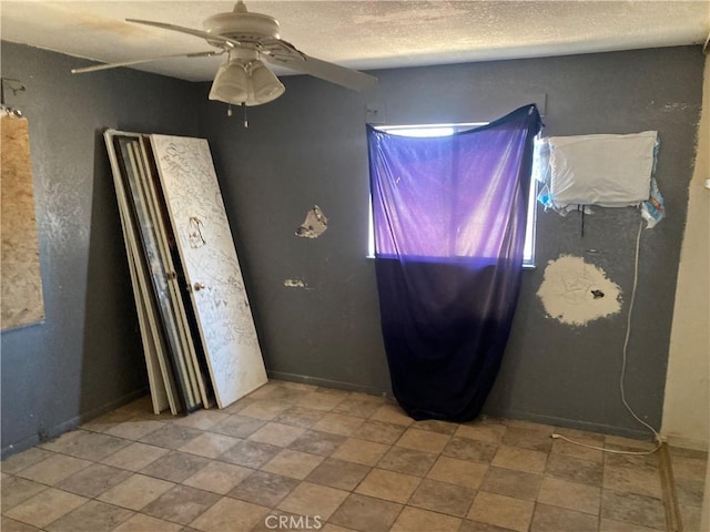 unfurnished bedroom with a textured ceiling, baseboards, and ceiling fan