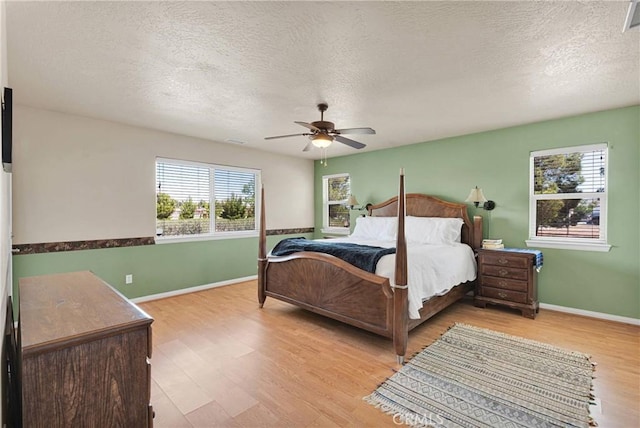 bedroom featuring light wood-style flooring, a textured ceiling, and multiple windows