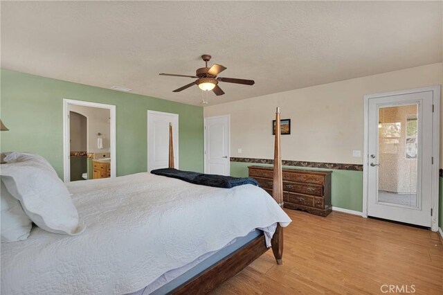 bedroom featuring wood finished floors, visible vents, a ceiling fan, baseboards, and ensuite bathroom