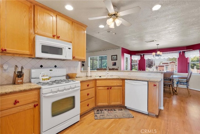 kitchen featuring a sink, decorative backsplash, white appliances, light wood-style flooring, and a peninsula