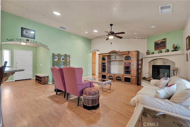 living area with arched walkways, wood finished floors, visible vents, and a ceiling fan