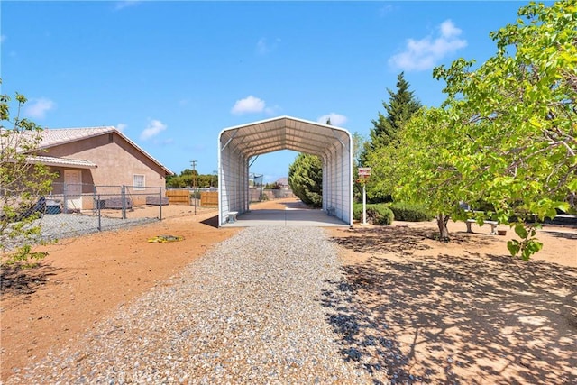 view of home's community featuring gravel driveway, a carport, and fence