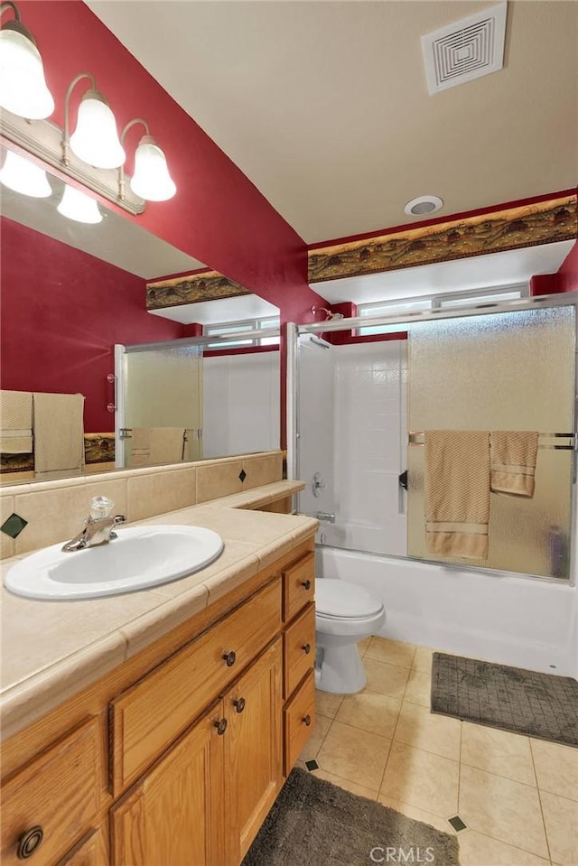 bathroom with tile patterned floors, shower / bath combination with glass door, toilet, visible vents, and vanity