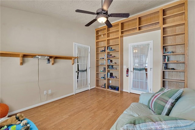 interior space featuring ceiling fan, baseboards, wood finished floors, and a textured ceiling