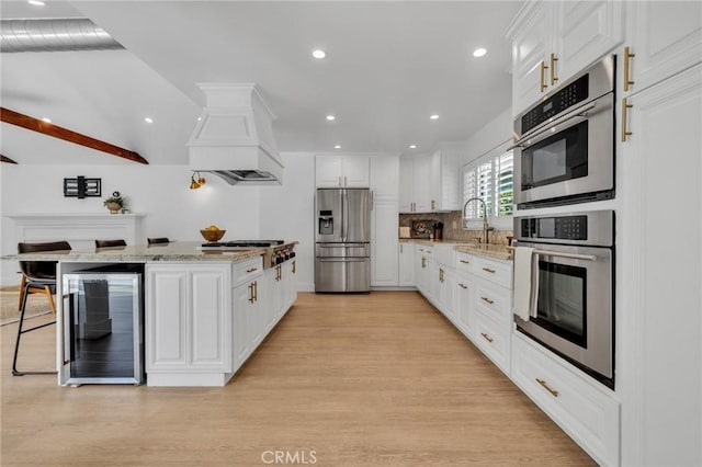 kitchen featuring stainless steel appliances, wine cooler, custom range hood, and light wood-style flooring