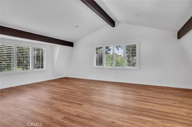unfurnished room featuring lofted ceiling with beams, baseboards, and light wood-type flooring