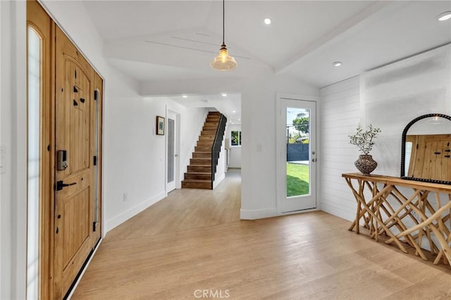 foyer entrance with vaulted ceiling, light wood-style flooring, baseboards, and stairway