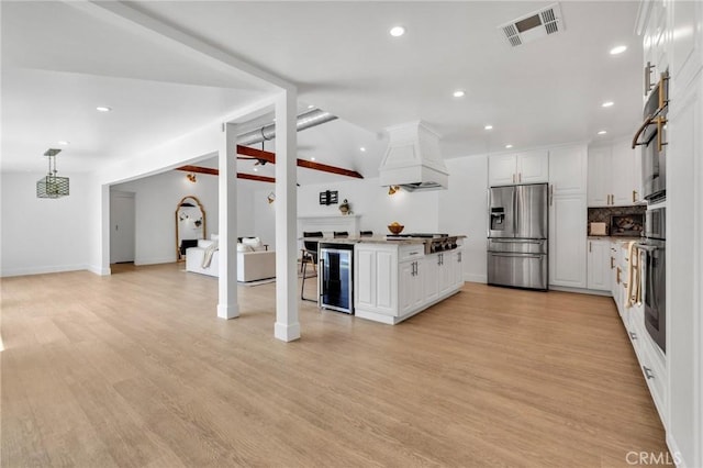 kitchen featuring wine cooler, visible vents, premium range hood, appliances with stainless steel finishes, and white cabinetry
