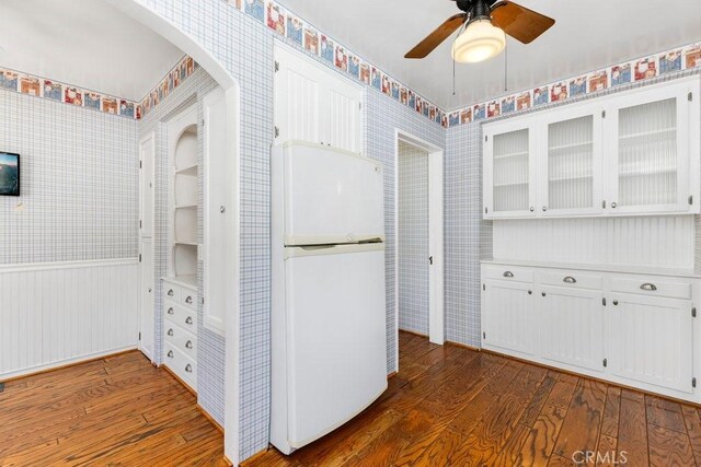 kitchen featuring dark wood-type flooring, freestanding refrigerator, glass insert cabinets, and wallpapered walls