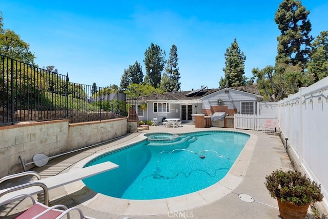 view of pool with a pool with connected hot tub, a patio, a fenced backyard, and a diving board