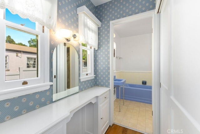 bathroom with wood finished floors and wallpapered walls