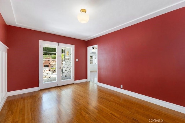 unfurnished room featuring baseboards, french doors, and wood finished floors