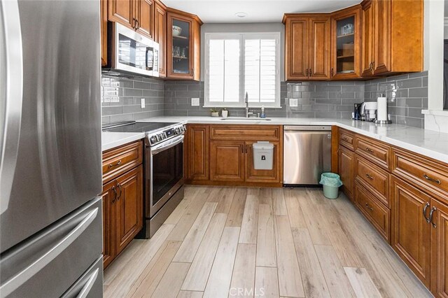 114 Via Estrada Unit B, Laguna Woods, CA 92637 - kitchen with stainless steel appliances, light wood-style floors, a sink, and brown cabinetry