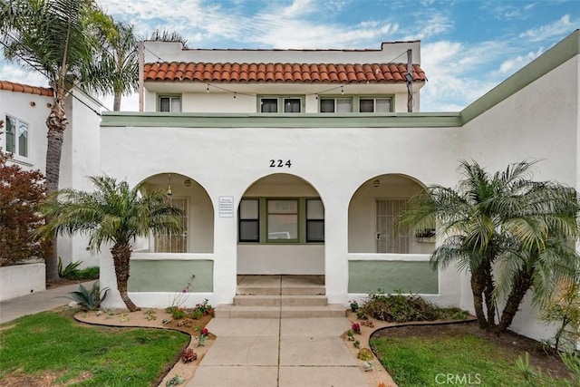 view of front of home with stucco siding, a tiled roof, and covered porch
