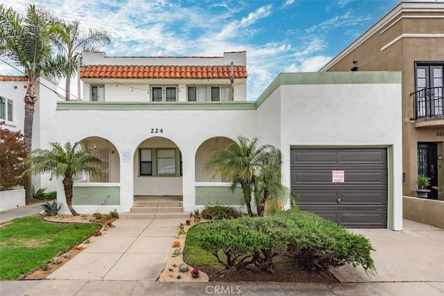 mediterranean / spanish-style home with a tiled roof, stucco siding, an attached garage, driveway, and covered porch
