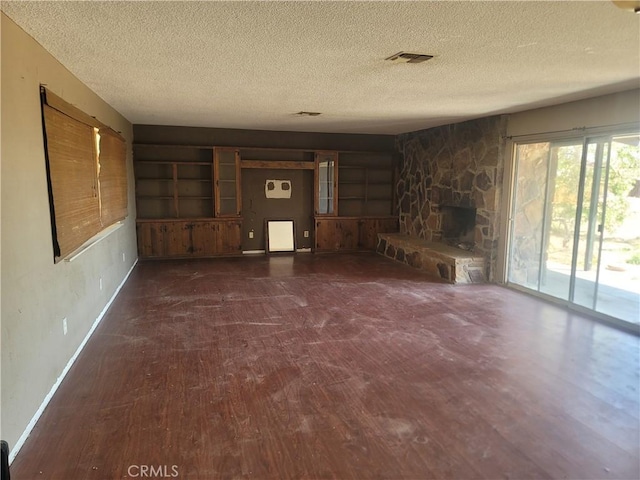 unfurnished living room featuring wood finished floors, a textured ceiling, baseboards, and visible vents