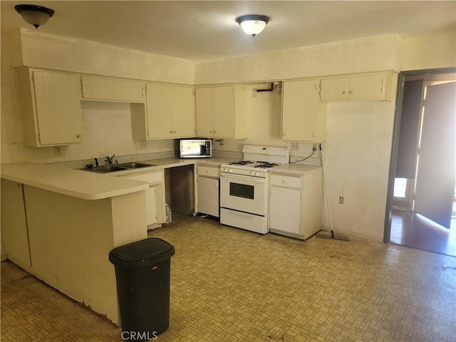 kitchen featuring light floors, light countertops, a sink, white gas stove, and a peninsula
