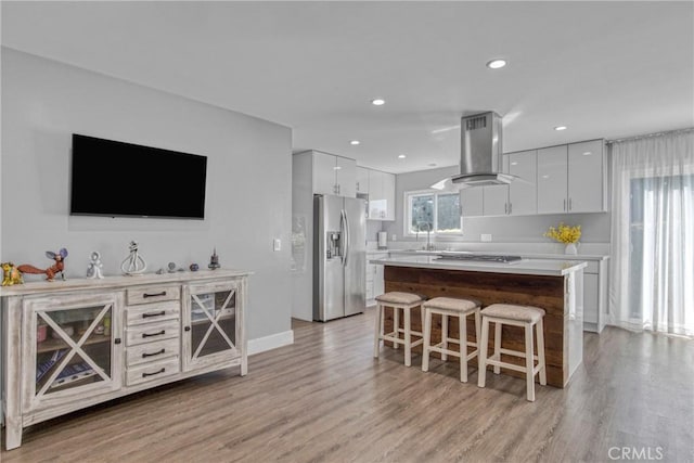7293 Cirrus Way, West Hills, CA 91307 - kitchen with stainless steel fridge, range hood, a breakfast bar area, white cabinets, and a sink