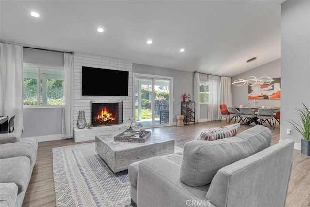 7293 Cirrus Way, West Hills, CA 91307 - living room with lofted ceiling, a brick fireplace, baseboards, wood finished floors, and a chandelier
