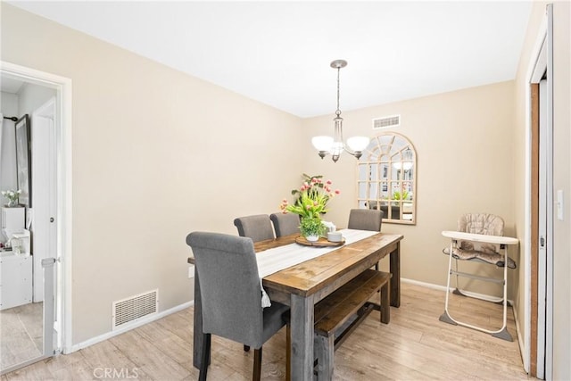 dining area featuring baseboards, light wood finished floors, a chandelier, and visible vents