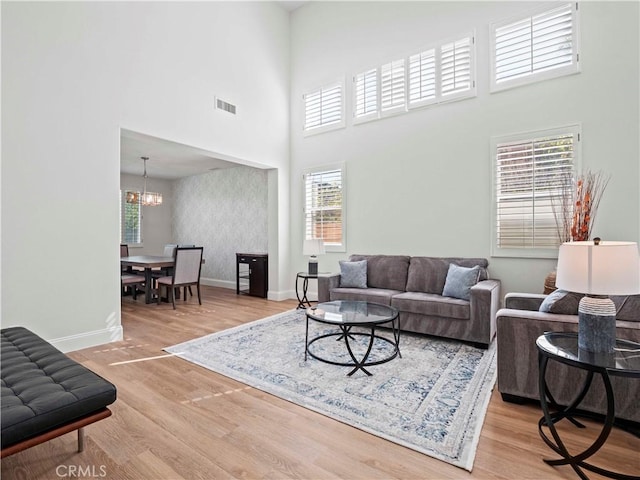 25626 Moore Ln, Stevenson Ranch, CA 91381 - living area with plenty of natural light, wood finished floors, a chandelier, a high ceiling, and baseboards