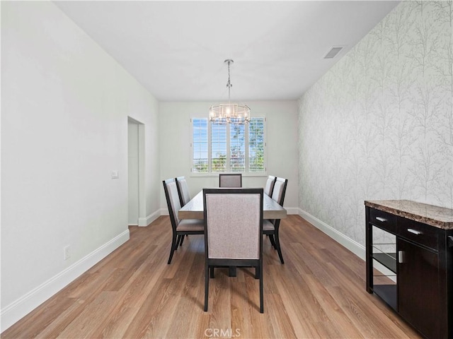 25626 Moore Ln, Stevenson Ranch, CA 91381 - dining area with wallpapered walls, a chandelier, baseboards, light wood-style floors, and an accent wall