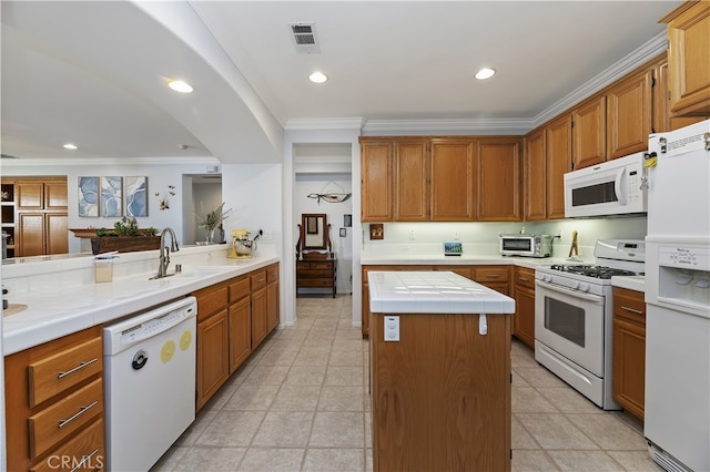 kitchen featuring tile countertops, a sink, white appliances, crown molding, and a center island