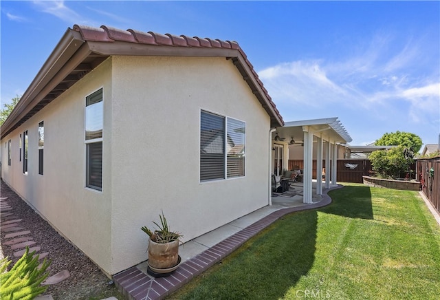 view of property exterior with a fenced backyard, a yard, stucco siding, ceiling fan, and a patio area