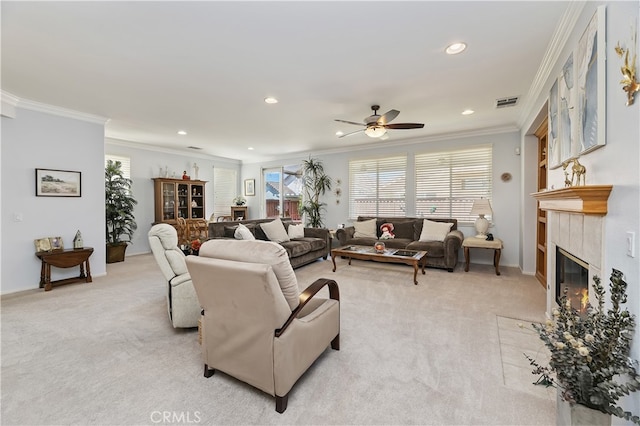 living room with a ceiling fan, a tile fireplace, light colored carpet, and crown molding