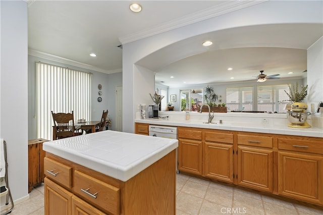 kitchen with arched walkways, tile counters, a sink, and recessed lighting