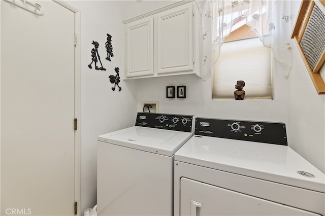 clothes washing area featuring washing machine and dryer and cabinet space