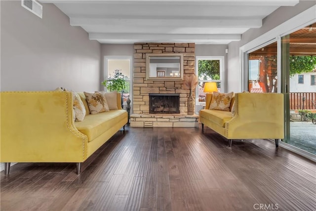 living room with dark wood-style floors, visible vents, beamed ceiling, and a fireplace