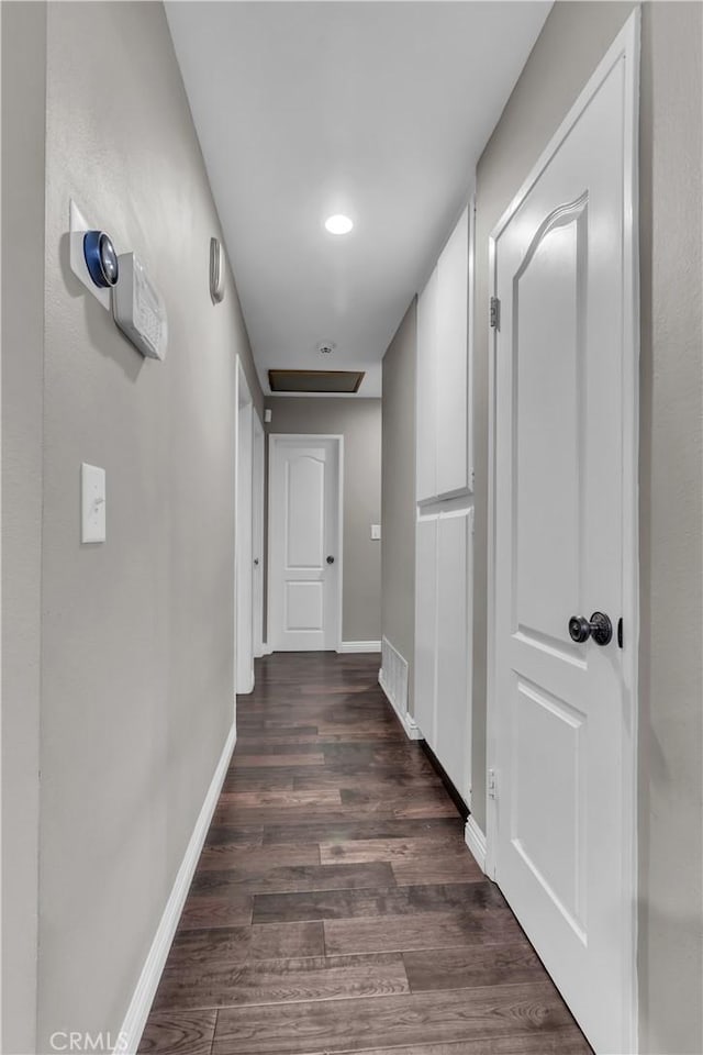 corridor featuring baseboards, visible vents, and dark wood-type flooring