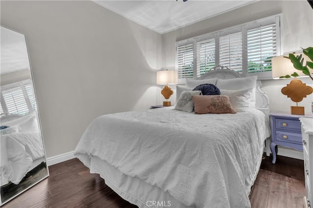 bedroom with multiple windows, wood finished floors, and baseboards