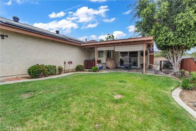 back of property with fence, a patio area, stucco siding, and a lawn