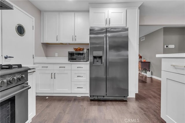 kitchen with dark wood-type flooring, stainless steel appliances, light countertops, and white cabinets